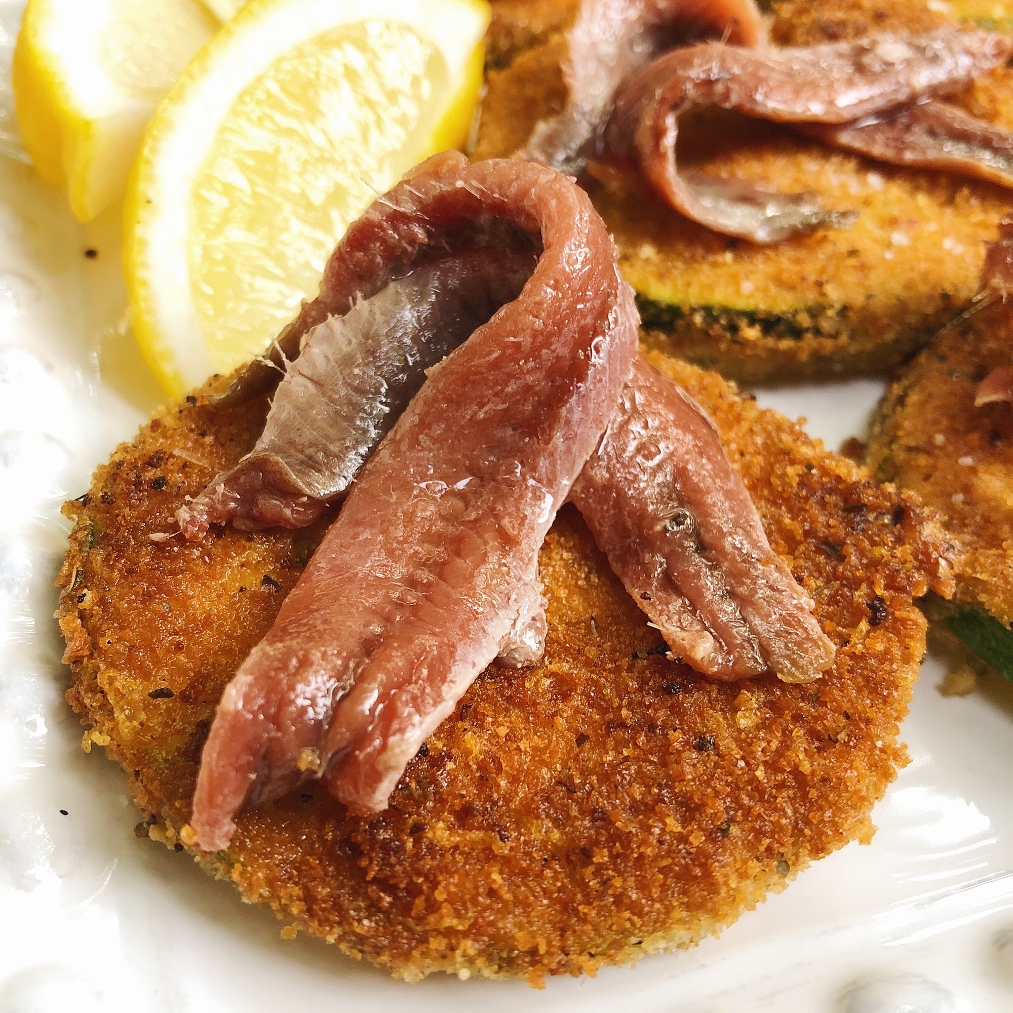 Cantabrian Anchovies and Pan-Fried Zucchini Chips with lemon on a plate - Donostia Foods