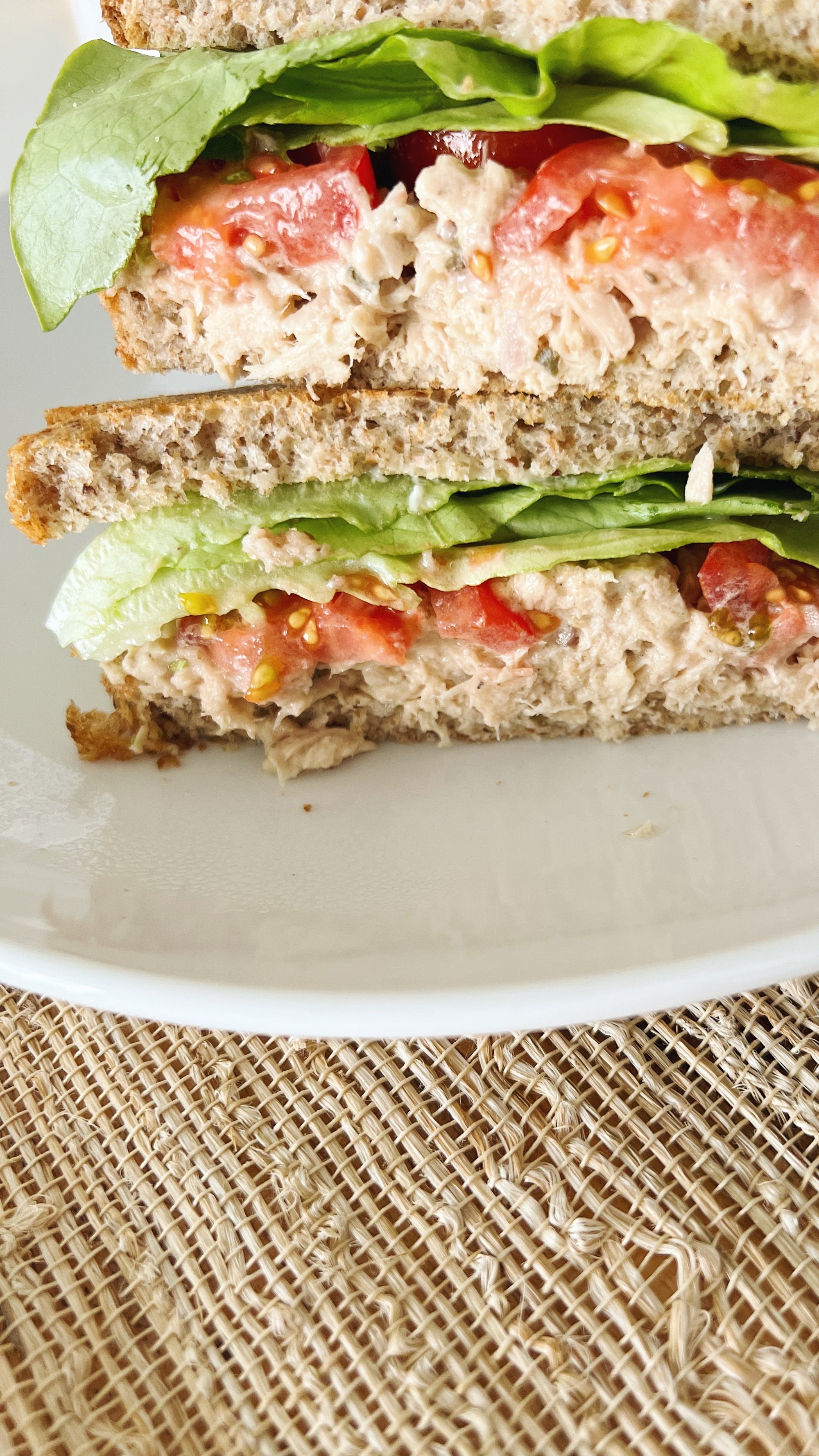 A Donostia Foods Bonito del Norte tuna salad sandwich with lettuce and tomato on a white plate.