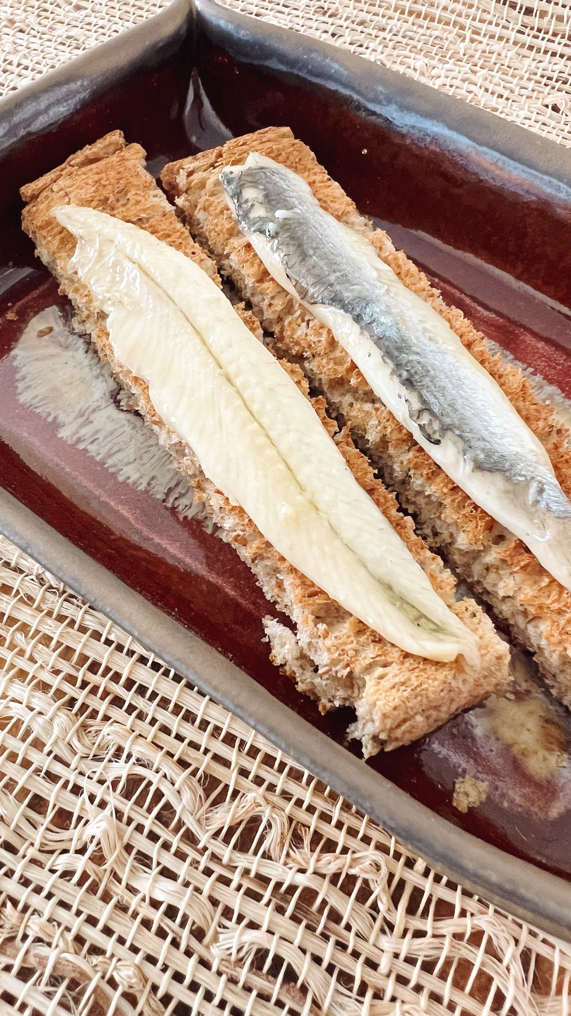 Donostia Foods Boquerones, white anchovy fillets, on slivers of toast and served on the red and gold Donostia Tinned Fish Dish.