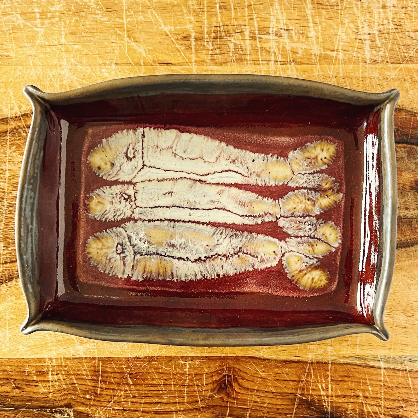Donostia Tinned Fish Dish - Three Fish Version No. 1 November 2025, red and gold and white, with hand drawn fish and pinched corners.