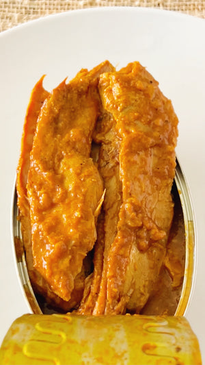 Close-up of an open tin of Donostia Foods Yellowfin Tuna Belly in Tikka Sauce with fillets out of the can slightly to show their girth in the luscious orange tikka sauce.